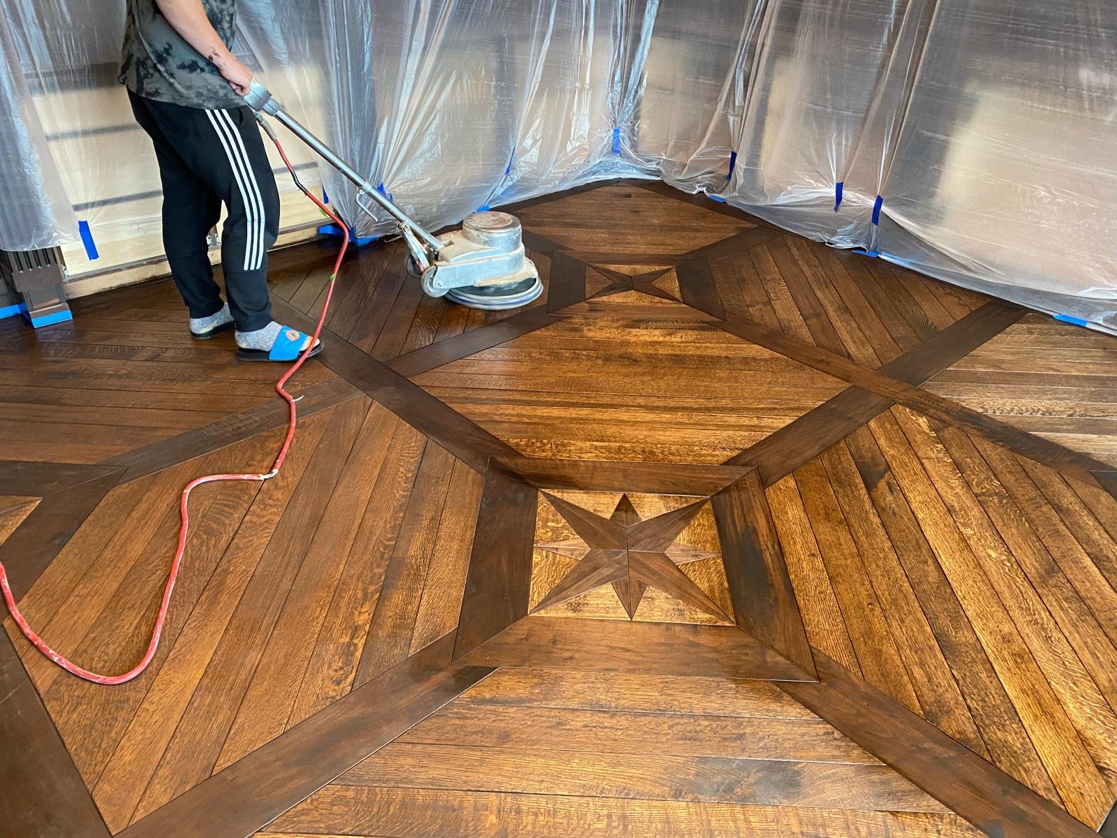 AG Floor Covering craftsman finishing a hand-laid star-pattern wood mosaic floor